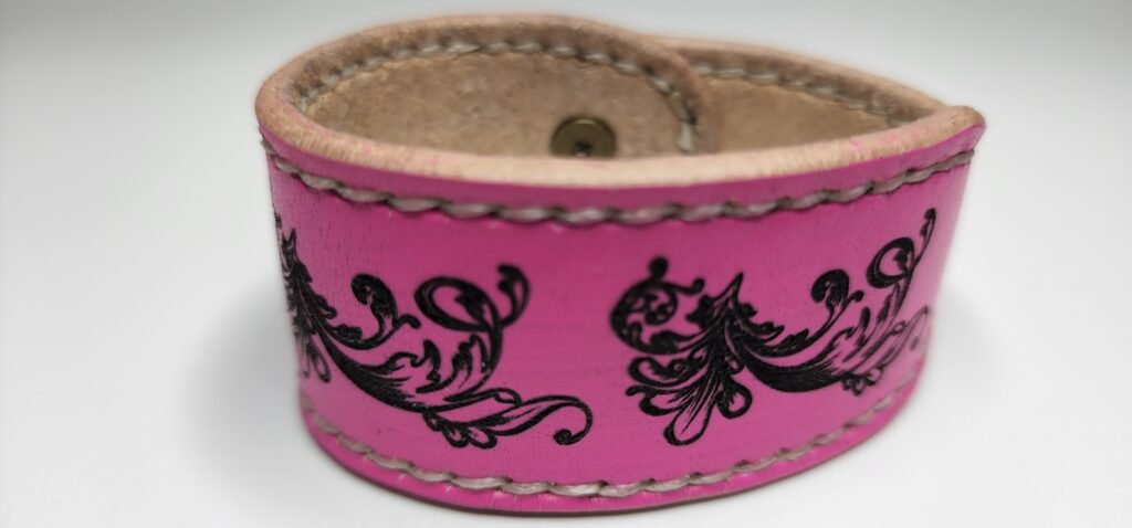 pulsera de cuero de color rosado fluorecente,con imagenes hechas con laser,cocida a mano con hilo nencerado